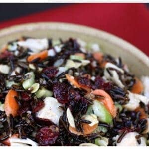turkey, carrots, celery, cranberries, and wild rice mixed together in a bowl