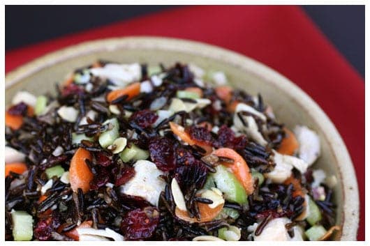 turkey, carrots, celery, cranberries, and wild rice mixed together in a bowl