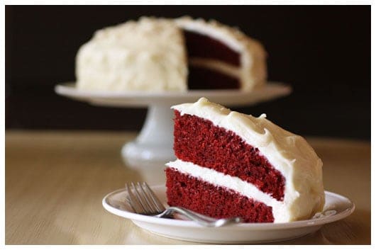 a slice of red velvet cake taken out of a whole cake