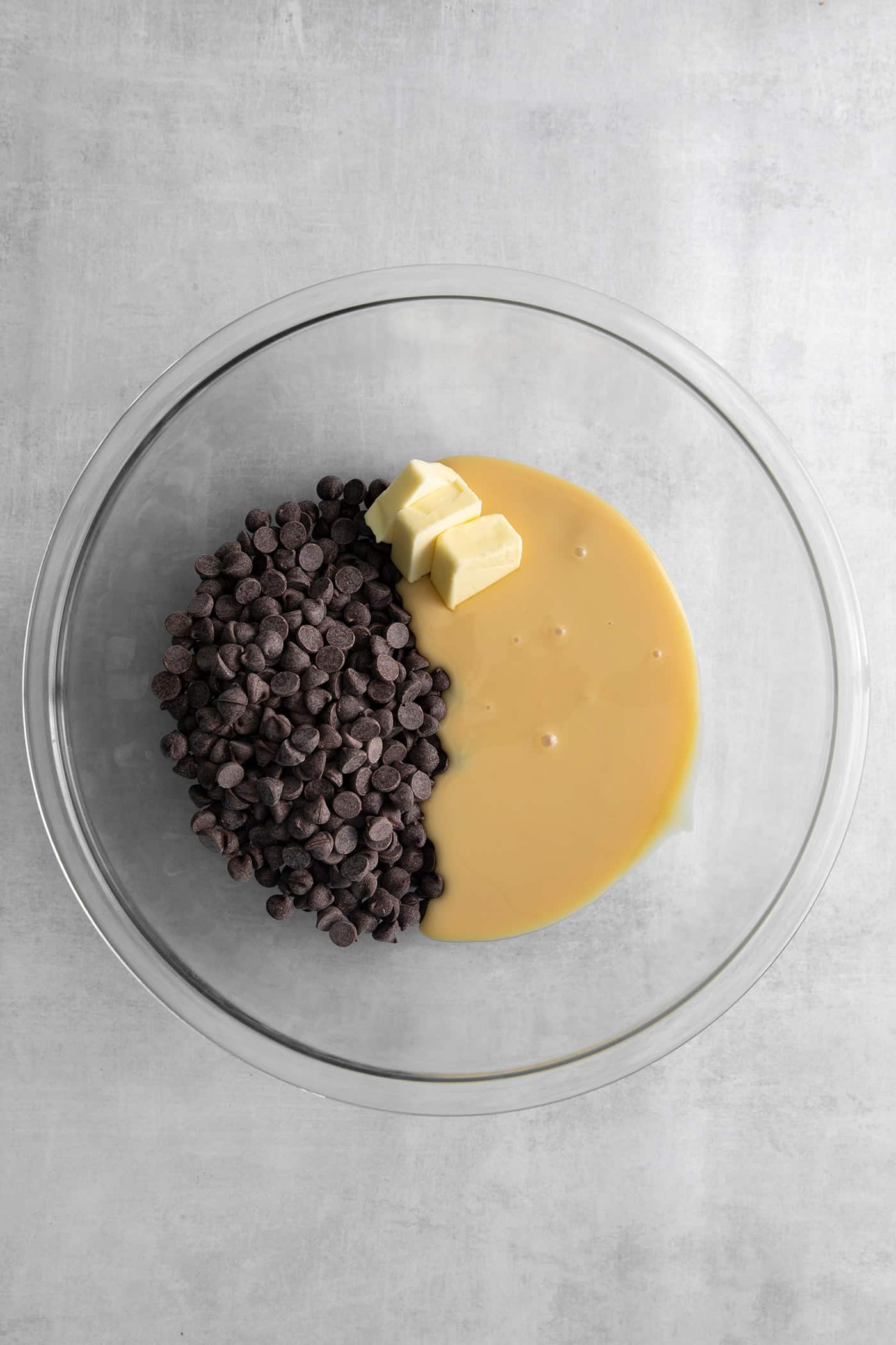 Chocolate chips, butter, and sweetened condensed milk in a glass bowl