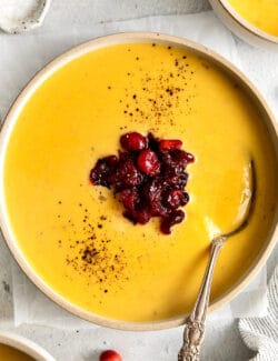 Overhead view of a bowl of squash soup with cranberry relish