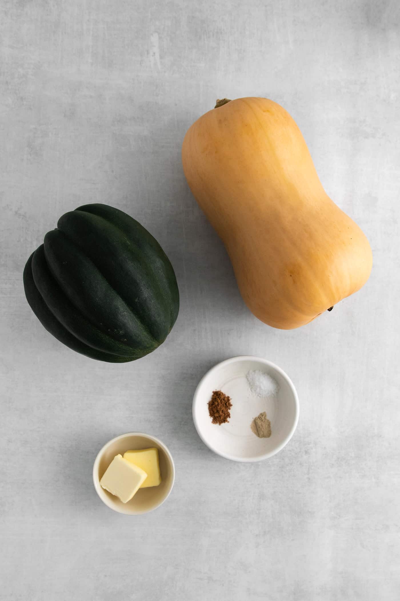 An acorn squash, butternut squash, butter, and spices