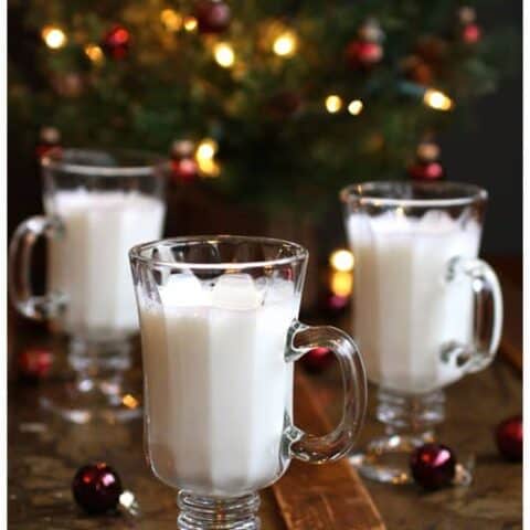 three glasses of almond steamer in front of a christmas tree