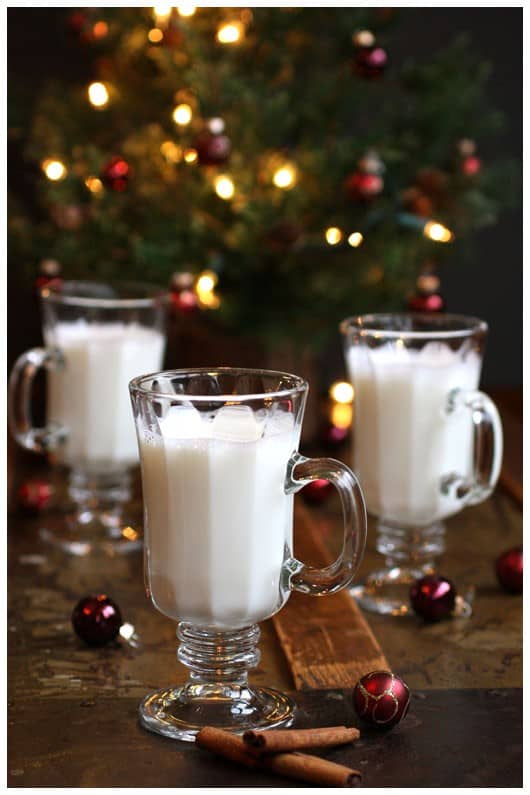 three glasses of almond steamer in front of a christmas tree