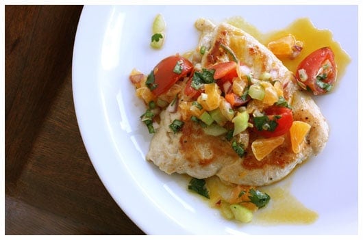 Chicken breast topped with clementine salsa on a white plate