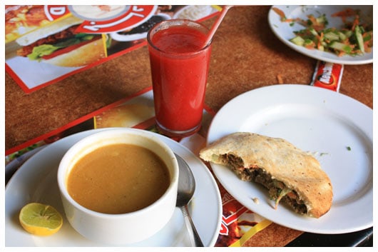 a bowl of lentil soup, shawarma, and a glass of strawberry juice