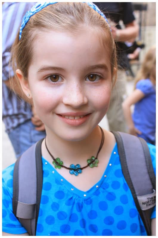 a girl wearing a blue and green flower necklace