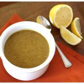 a white bowl of lentil soup with fresh lemon