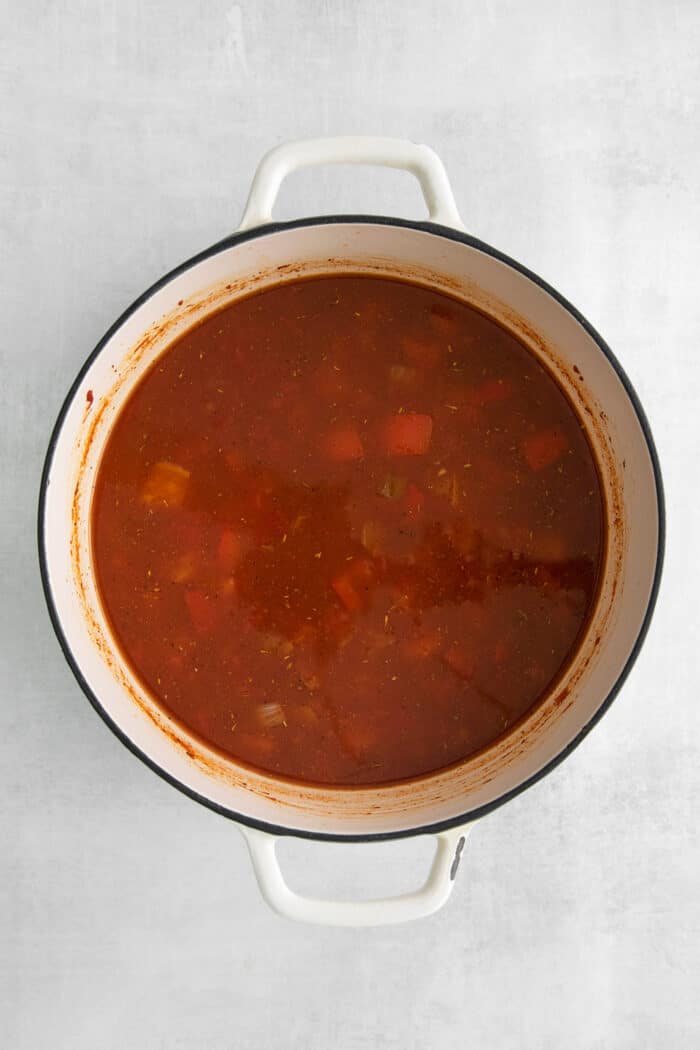 Chicken broth and tomato paste in a soup pot with vegetables