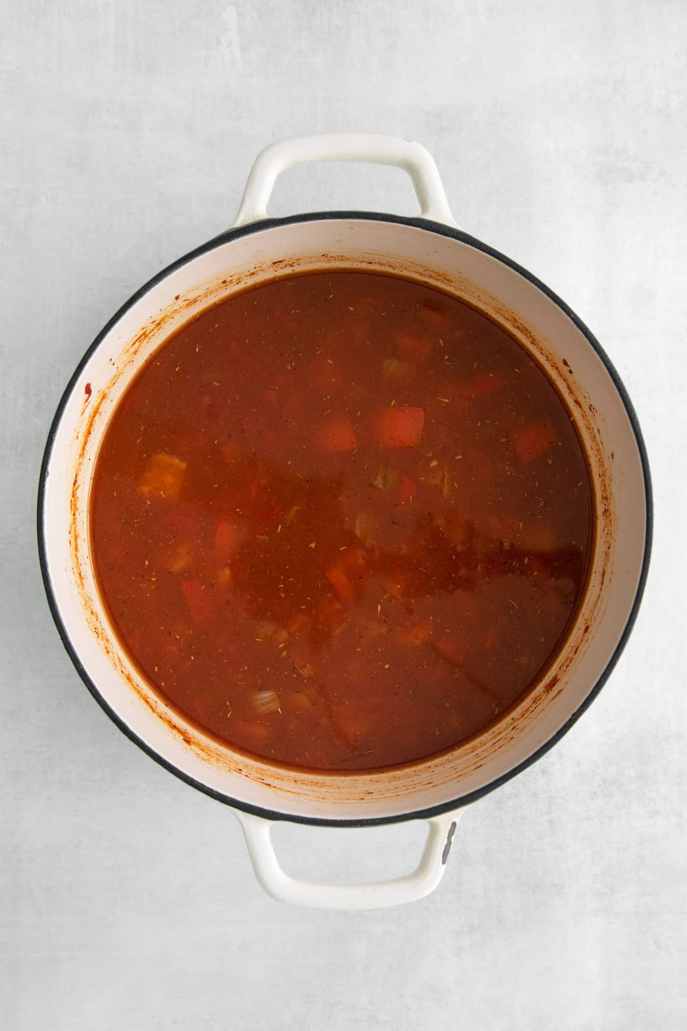 Chicken broth and tomato paste in a soup pan with vegetables