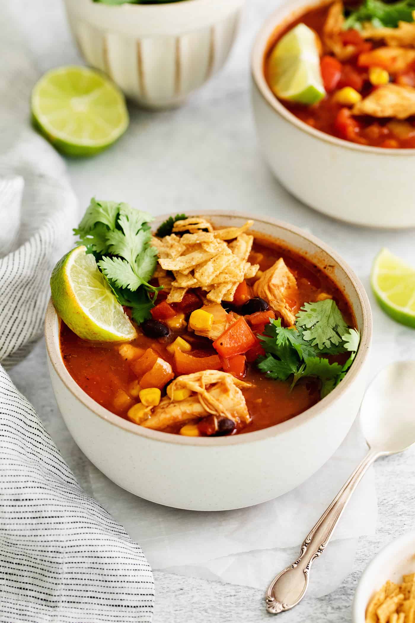 Angled view of a bowl of chicken tortilla soup topped with lime and cilantro