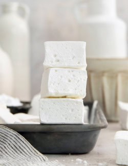 Stack of 3 homemade marshmallows on edge of sheet pan