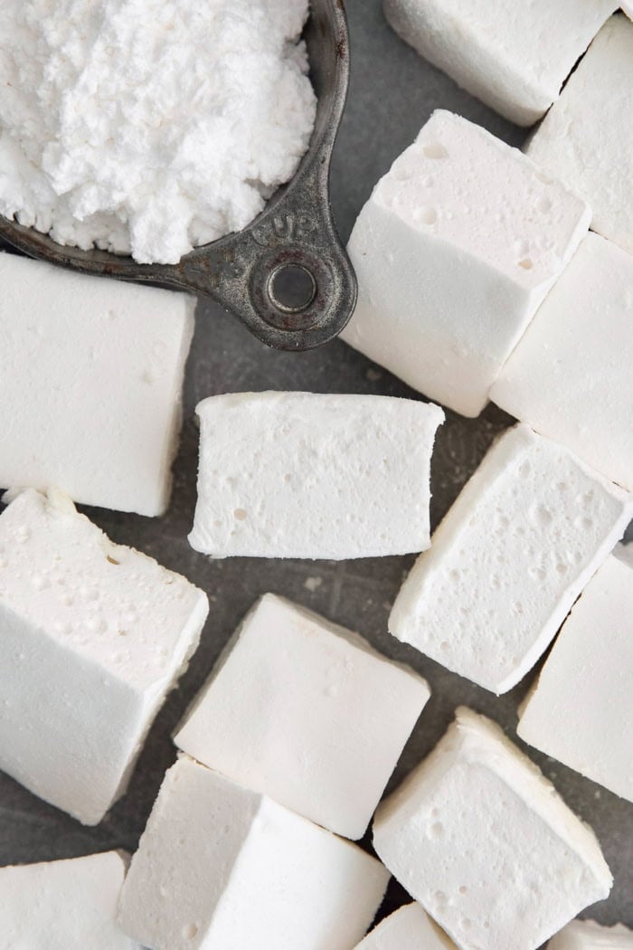 Overhead view of homemade marshmallows and powdered sugar in cup