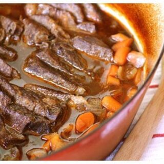 Slices of pot roast with carrots in a dutch oven