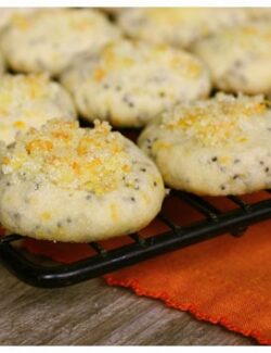 a black cooling rack with orange poppy seed cookies