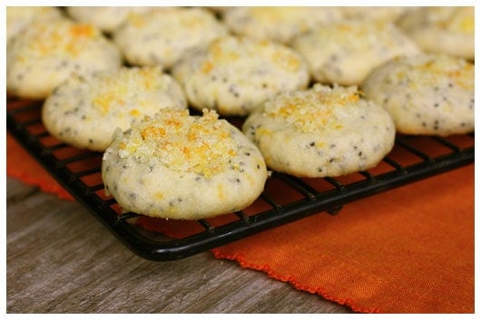 a black cooling rack with orange poppy seed cookies