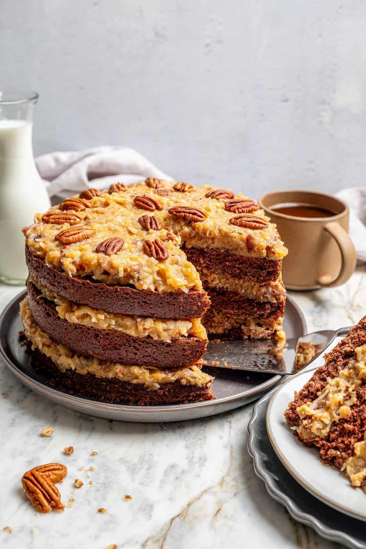 German chocolate cake on platter with one slice removed to show layers