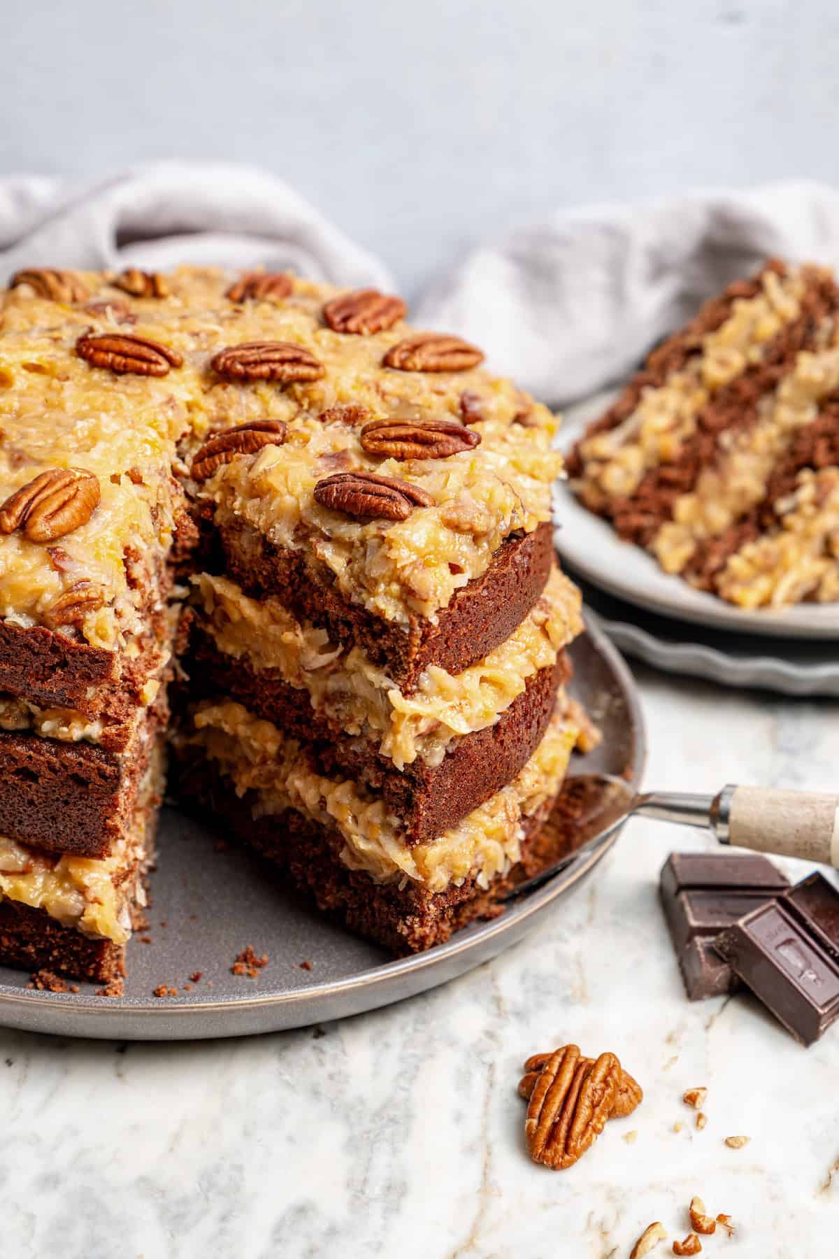 German chocolate cake on platter with one slice removed to show layers