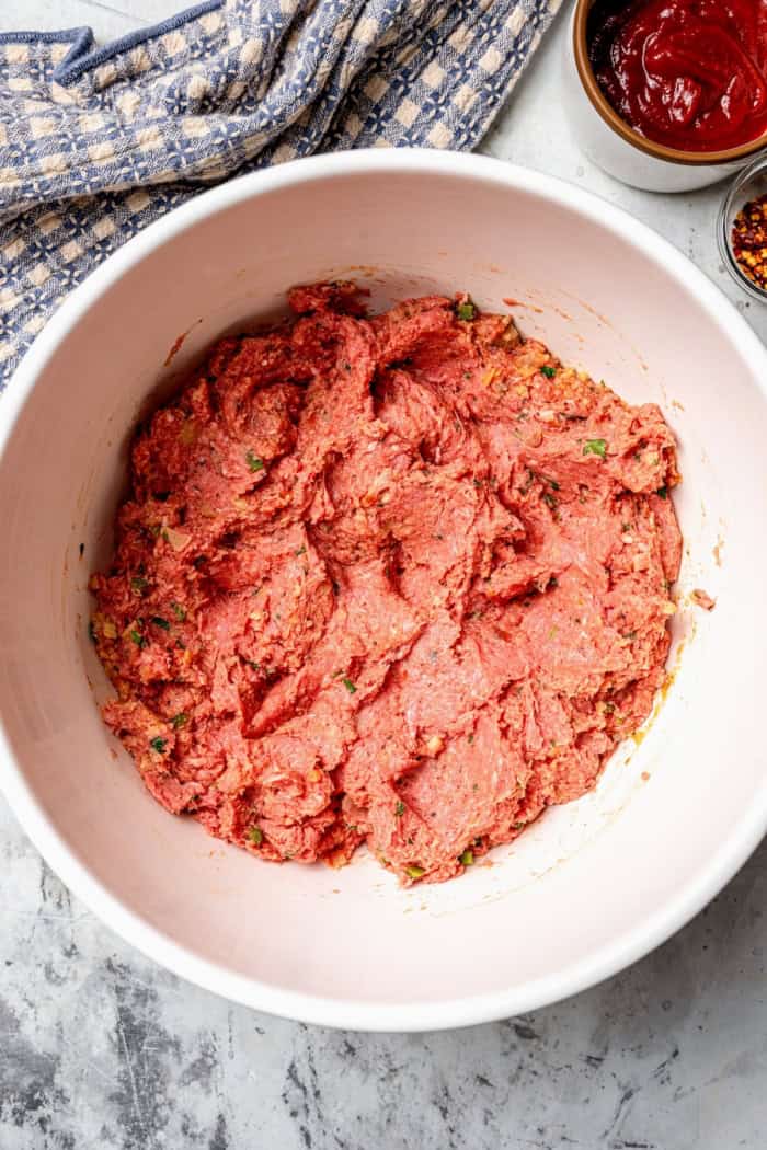Ground beef meatloaf mixture in mixing bowl.