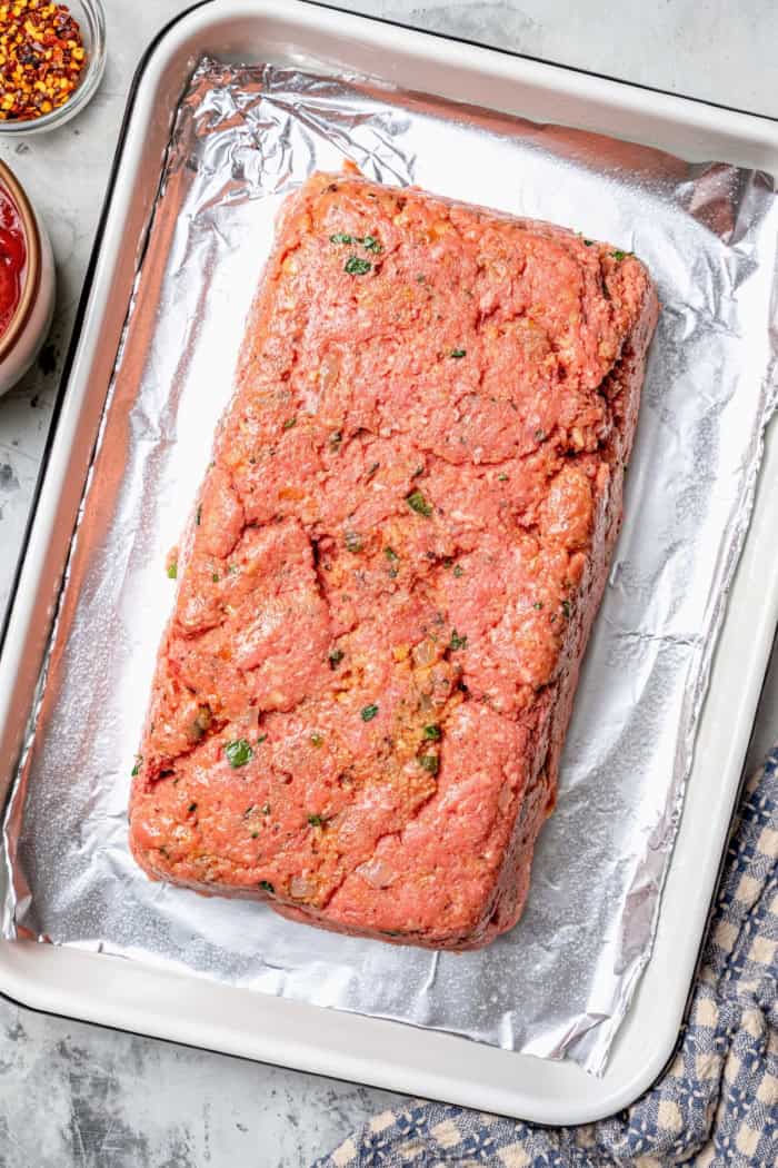 Ground beef mixture shaped into loaf on pan.