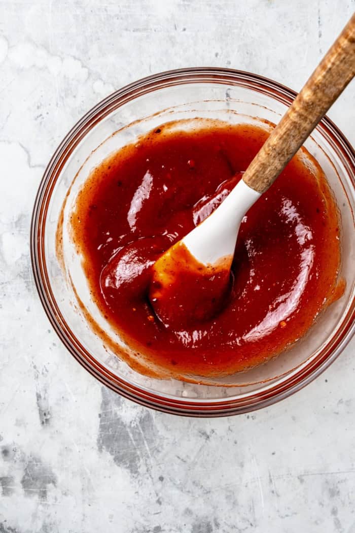 Spicy meatloaf sauce in glass bowl with spoon.