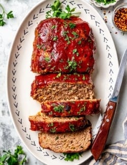 Spicy meatloaf on platter with 4 slices cut.