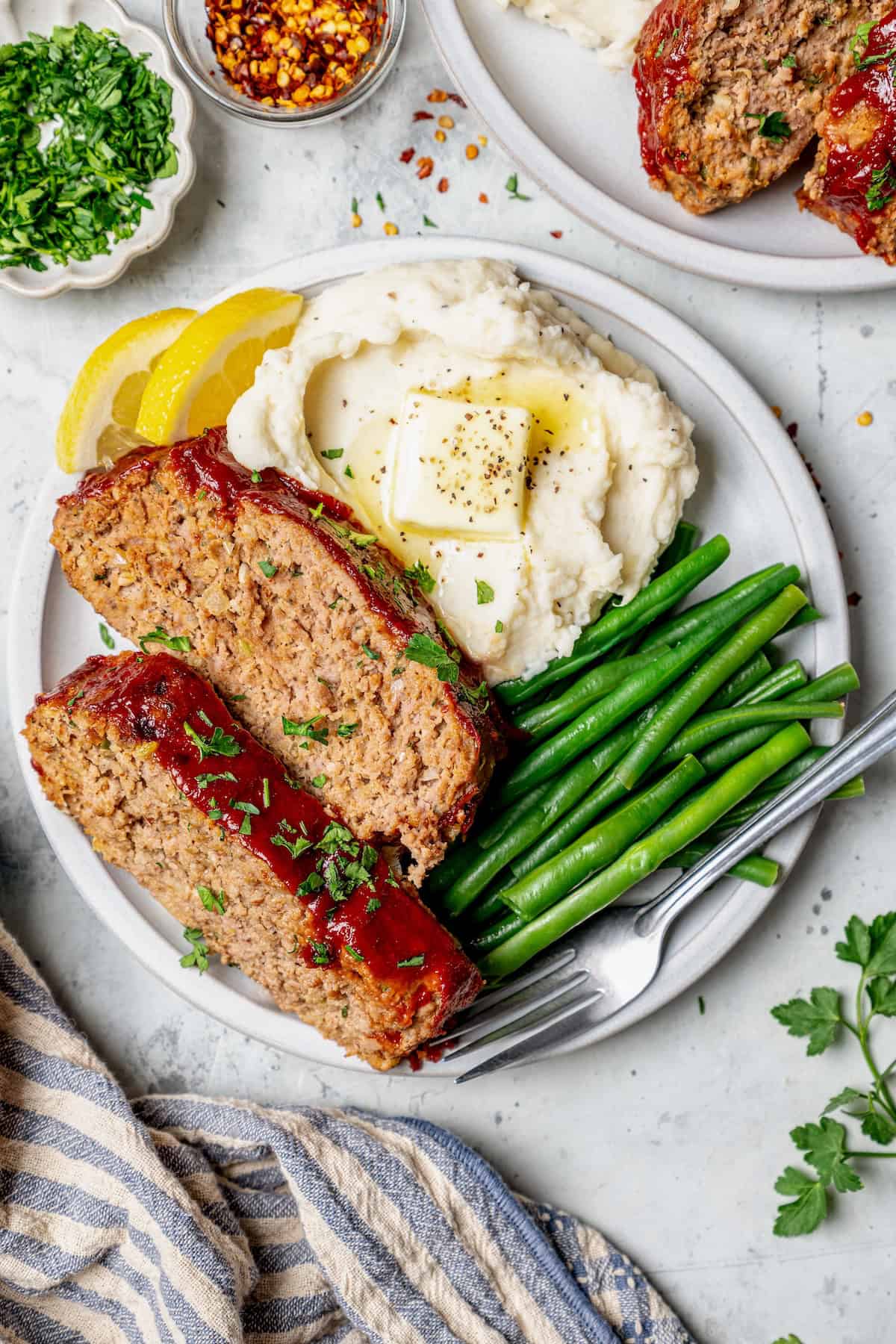 Plate with two spices of spicy meatloaf, green beans, and mashed potatoes.