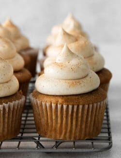 Snickerdoodle cupcakes with cream cheese frosting on a cooling