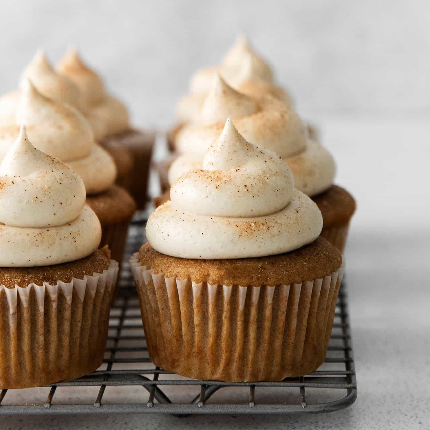 Snickerdoodle cupcakes with cream cheese frosting on a cooling