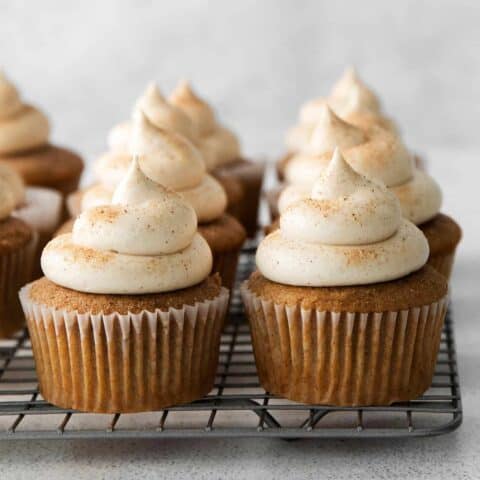 Snickerdoodle cupcakes with cream cheese frosting on a cooling