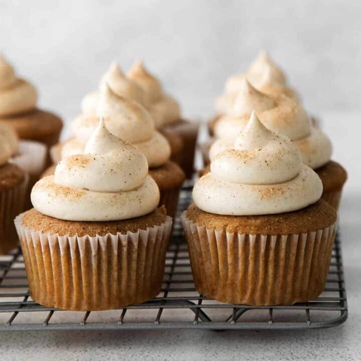 Snickerdoodle cupcakes with cream cheese frosting on a cooling
