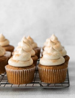 Snickerdoodle cupcakes with cream cheese frosting on a cooling