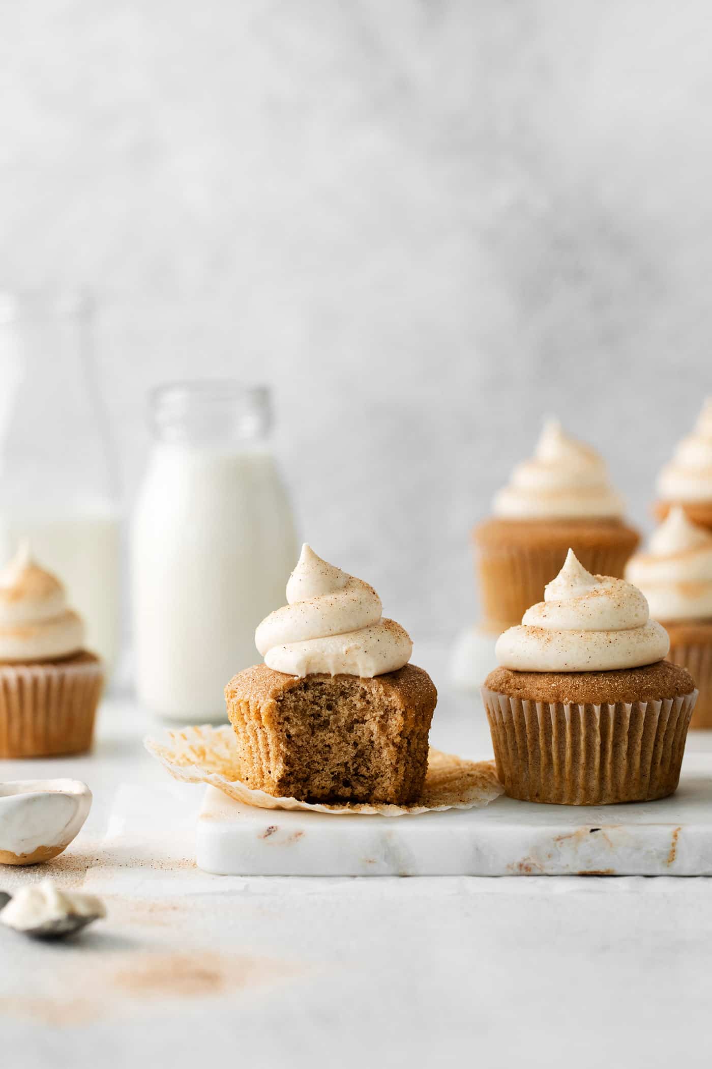 Snickerdoodle cupcakes with cream cheese frosting, one with a bite missing