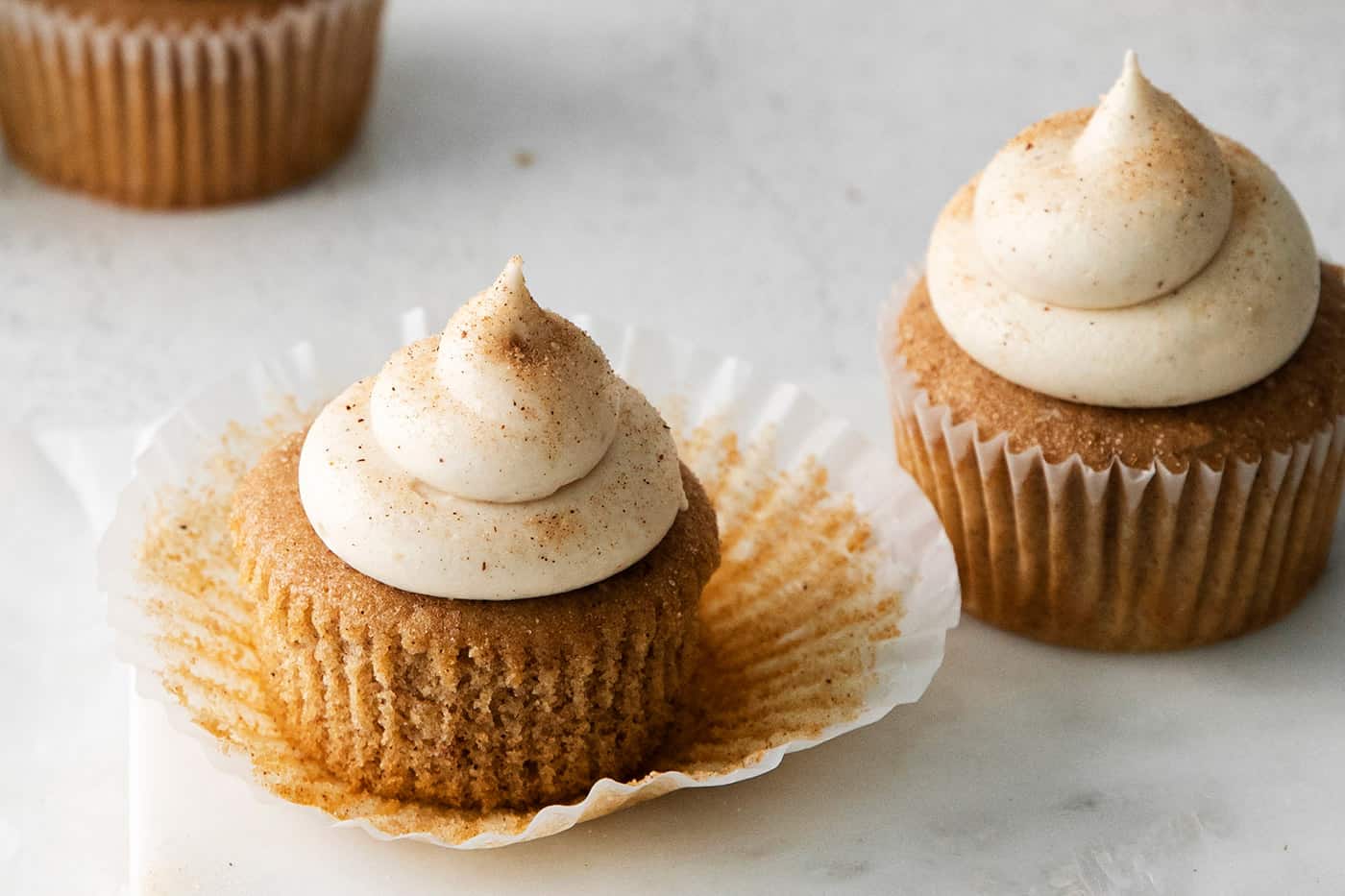 Two snickerdoodle cupcakes with cream cheese frosting