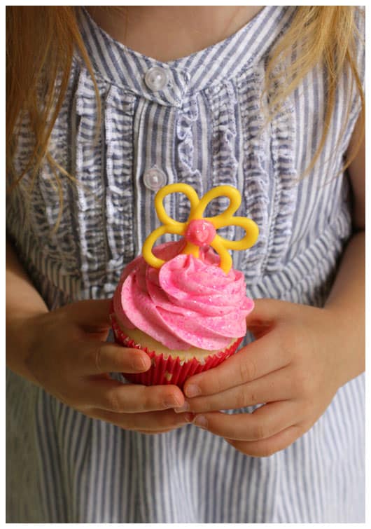 a girl holding a pink cupcake