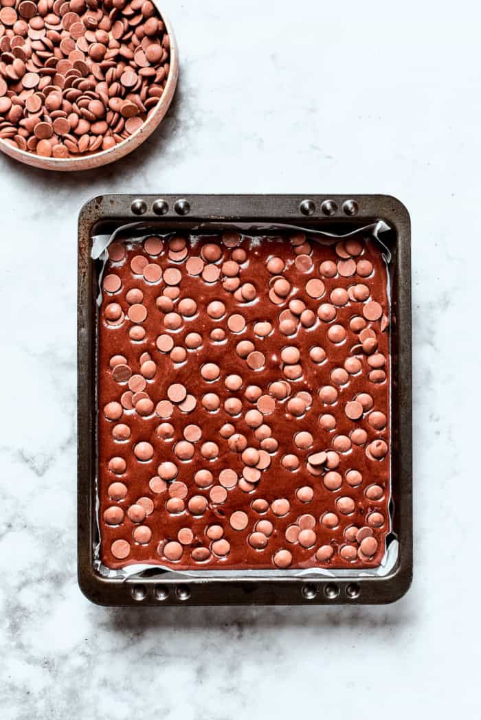 Overhead view of chocolate chips added to pan of brownie batter