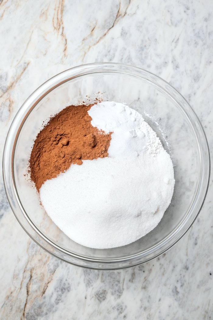 Dry ingredients for chocolate cake in glass bowl before whisking.