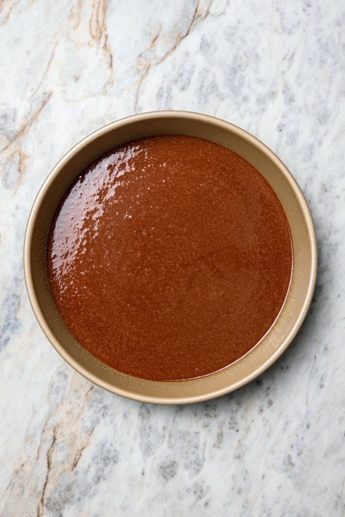 Chocolate cake batter in round pan.