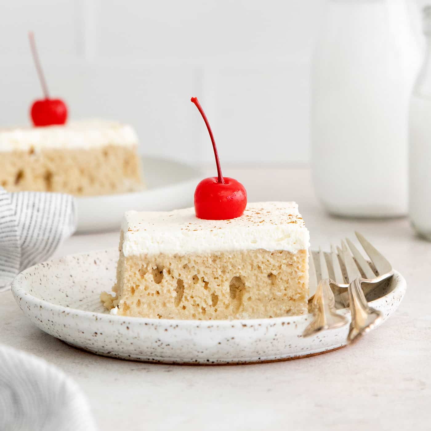 A slice of tres leches cake on a white plate