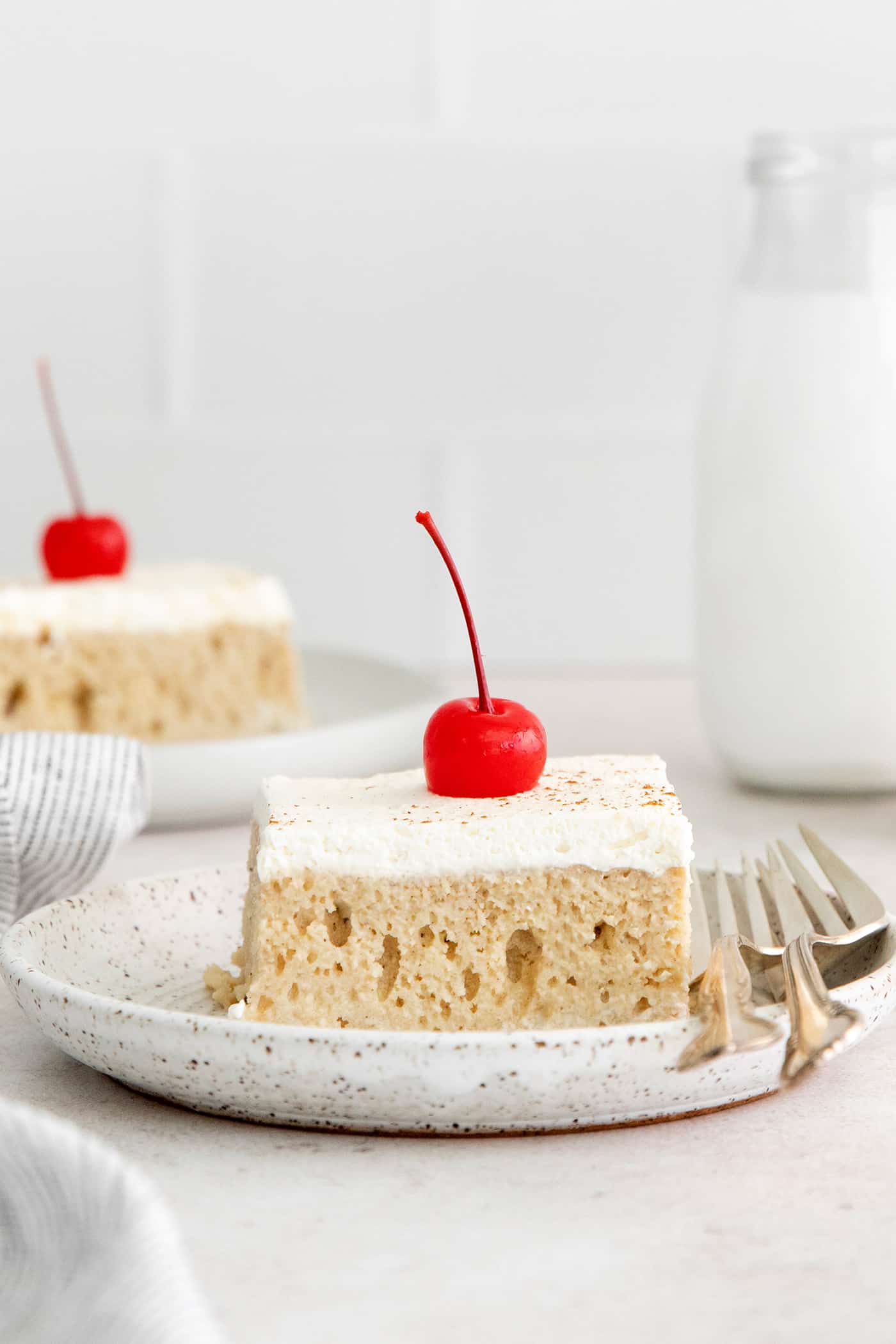 A slice of tres leches cake on a white plate