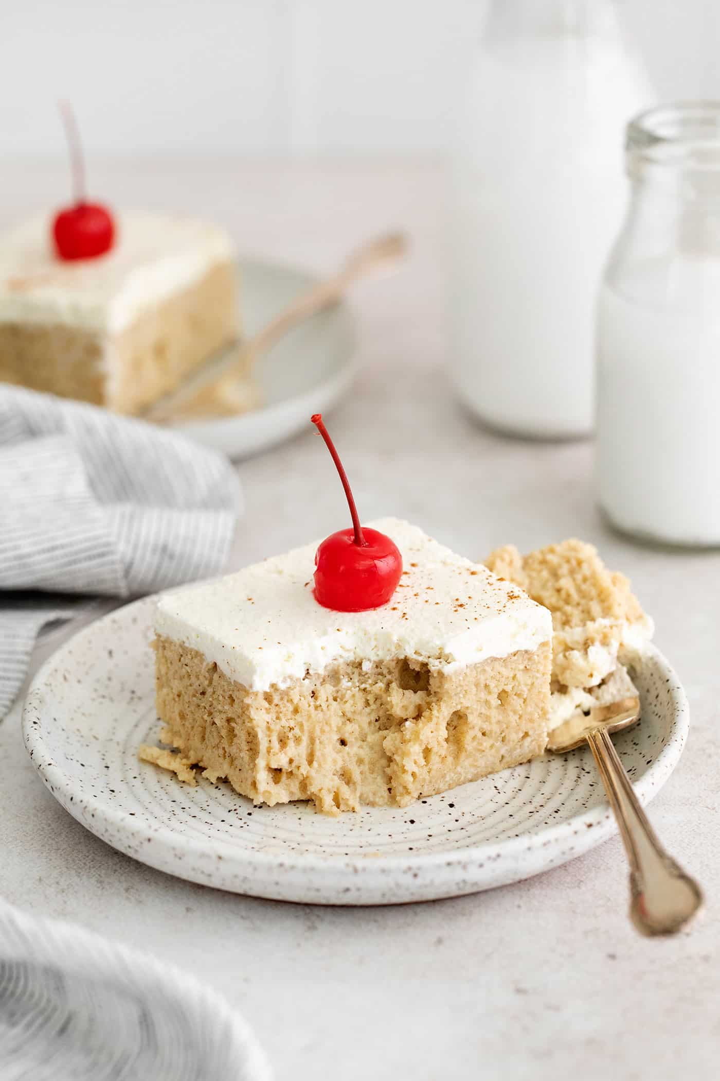 A slice of tres leche cake with a spoonful missing