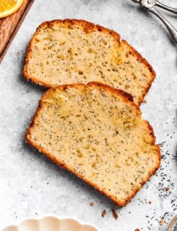 Two slices of orange glazed poppy seed bread on countertop.