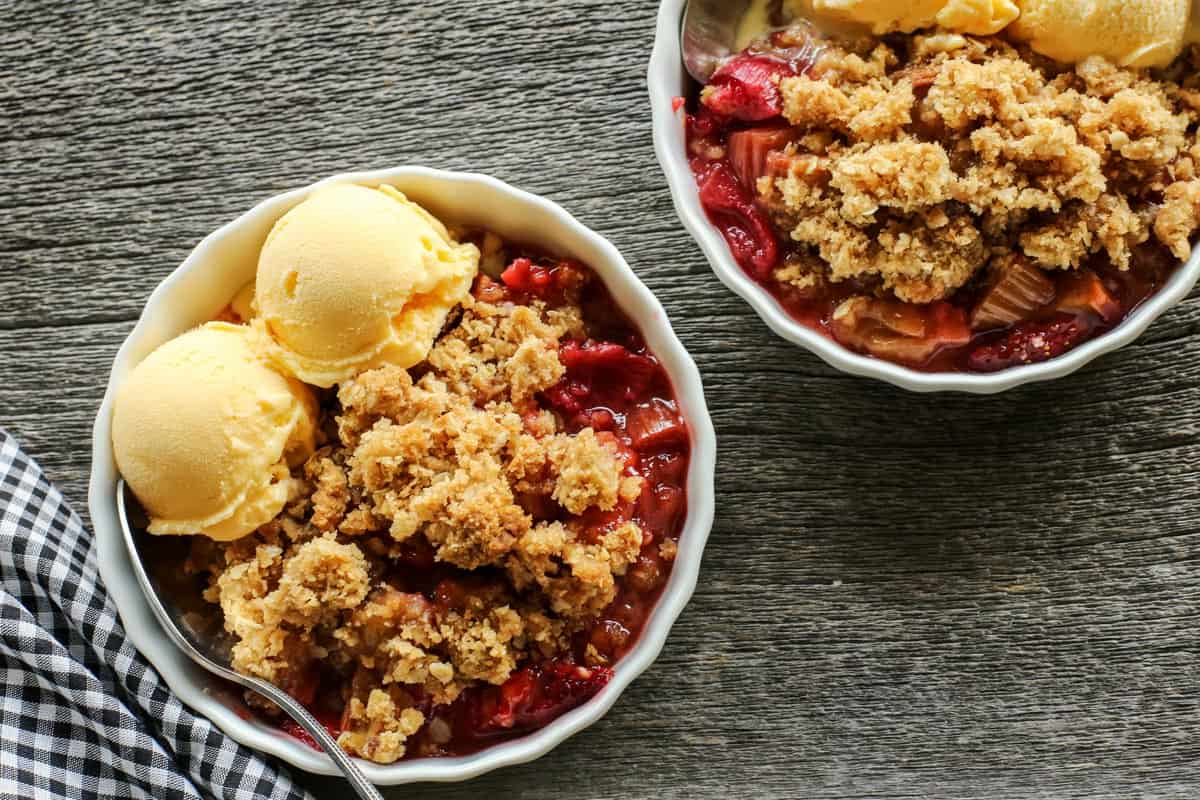 rhubarb and strawberry crisp in individual bowls with scoops of vanilla ice cream
