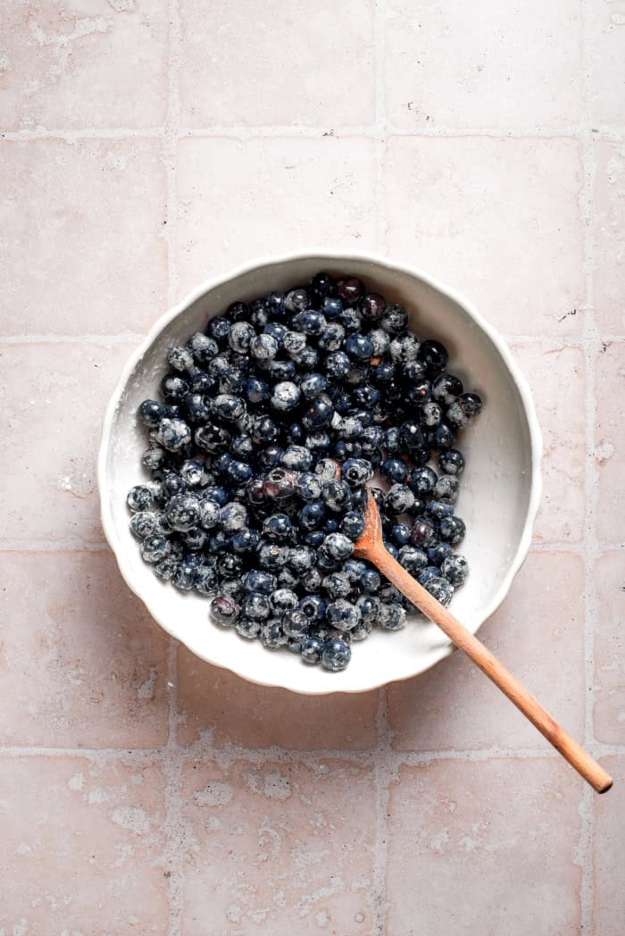 Blueberry filling mixture in bowl with wooden spoon.