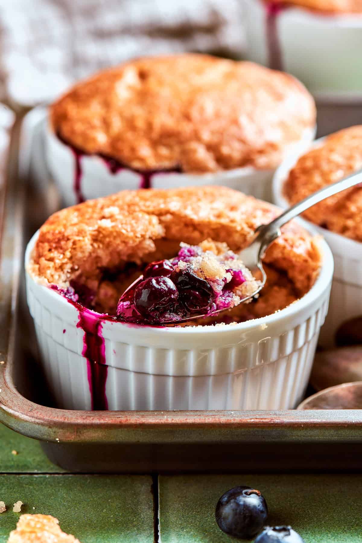 Spoonful of blueberry cobbler in ramekin.