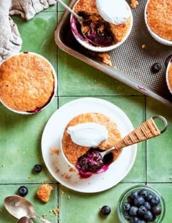 Mini blueberry cobblers on sheet pan, countertop, and plate.