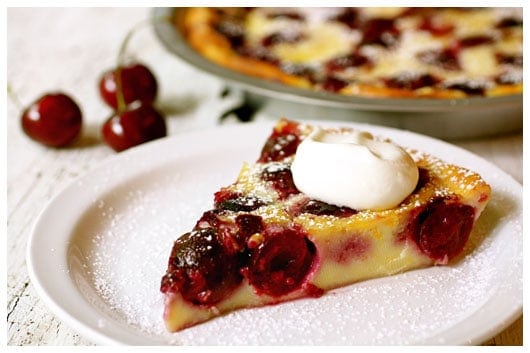 a slice of cherry clafouti topped with whipped cream