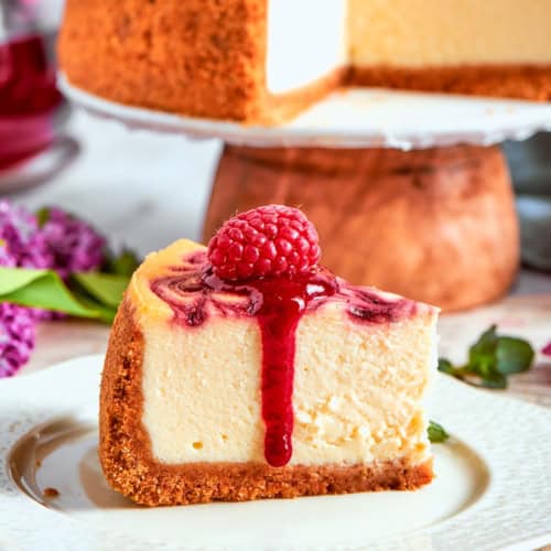 Slice of raspberry swirl cheesecake topped with raspberry sauce and fresh berry