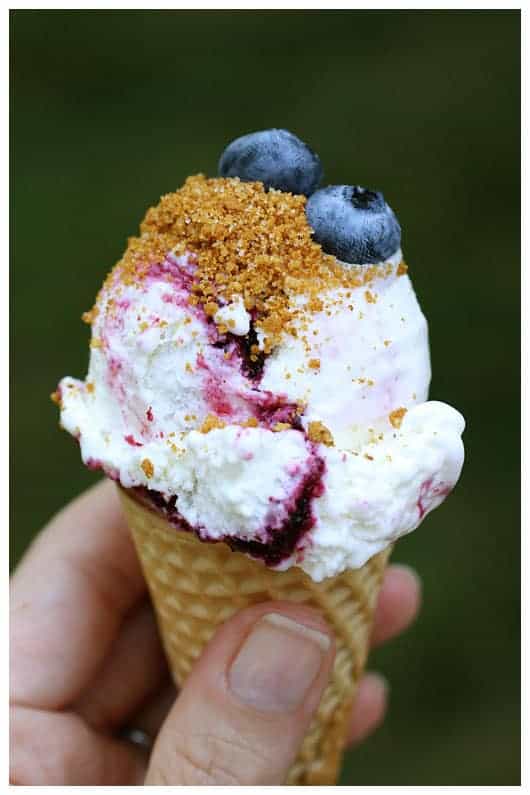 a scoop of blueberry cheesecake ice cream on a cone