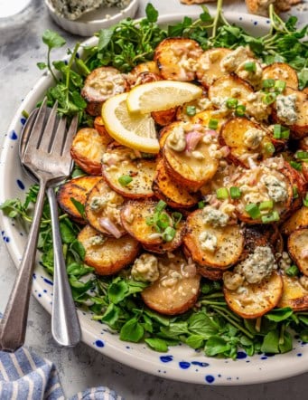 Grilled potato salad with blue cheese vinaigrette on platter with two forks